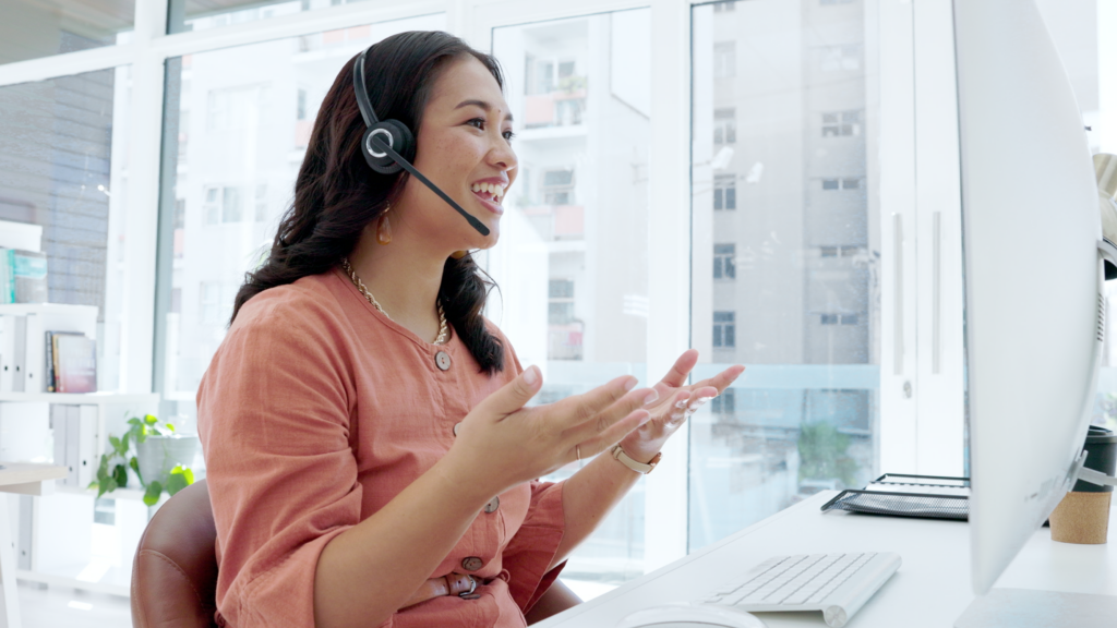 A recruiter smiles and chats with a candidate via a Zoom call on her computer.